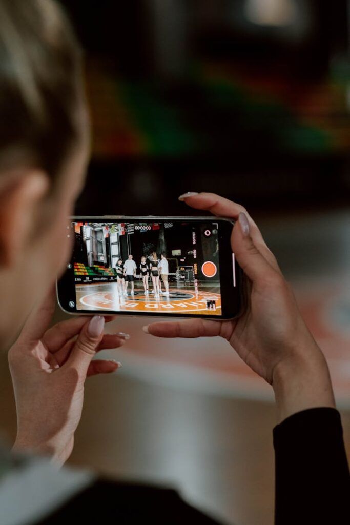 pexels photo 7335868 A person recording a cheerleading group with a smartphone during practice indoors.